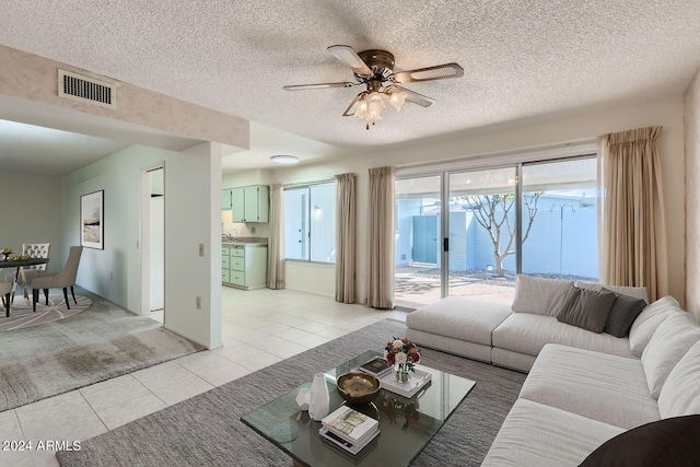 living room featuring ceiling fan, light tile patterned floors, and a textured ceiling