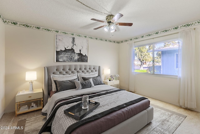 bedroom with ceiling fan, carpet flooring, and a textured ceiling