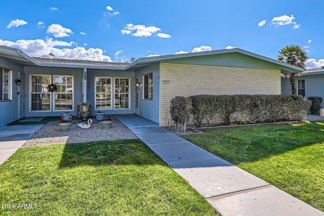property entrance with a yard and brick siding