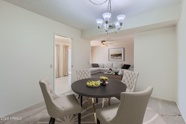 dining space featuring light carpet, a textured ceiling, and ceiling fan with notable chandelier