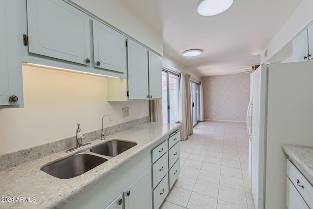 kitchen featuring light tile patterned flooring, sink, white cabinetry, white refrigerator with ice dispenser, and light stone countertops