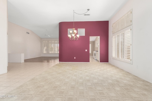 spare room featuring ceiling fan with notable chandelier, lofted ceiling, and light colored carpet