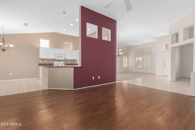 unfurnished living room featuring ceiling fan, light wood-type flooring, and vaulted ceiling