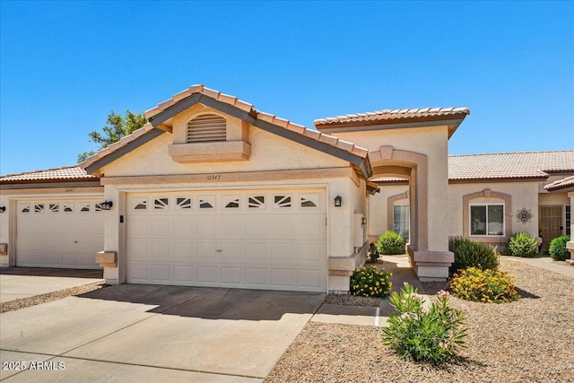 mediterranean / spanish-style house with a tiled roof, driveway, a garage, and stucco siding