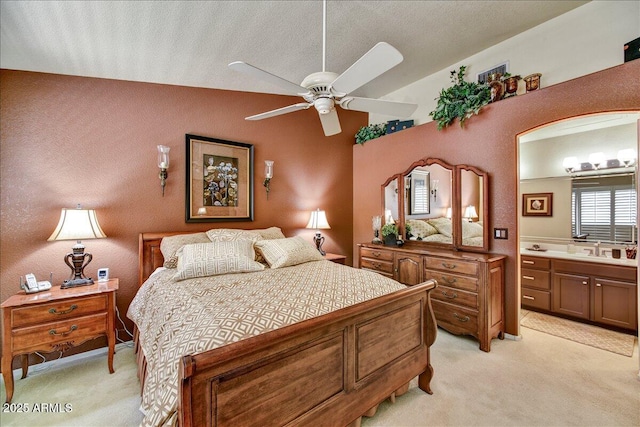 bedroom with light colored carpet, a sink, ensuite bathroom, and ceiling fan