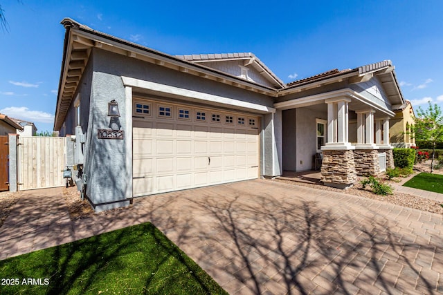 view of front of home with a gate, driveway, an attached garage, stucco siding, and a tile roof