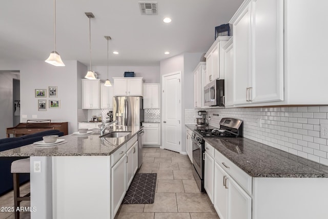 kitchen with visible vents, a breakfast bar, a sink, stainless steel appliances, and white cabinetry