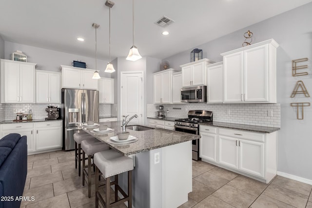 kitchen with a breakfast bar, stainless steel appliances, hanging light fixtures, white cabinetry, and a sink