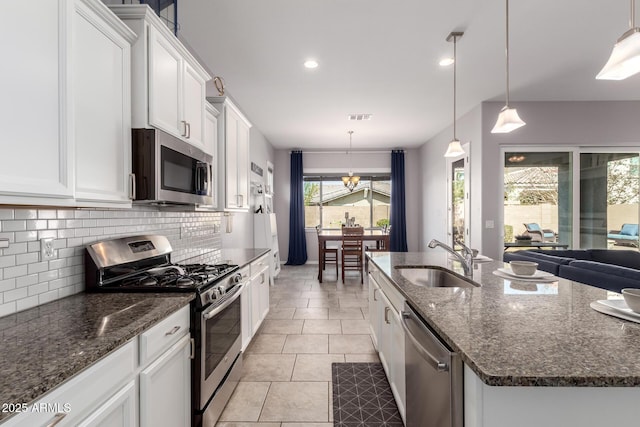 kitchen featuring tasteful backsplash, visible vents, a sink, appliances with stainless steel finishes, and a kitchen island with sink