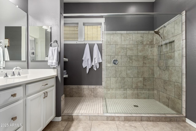 full bath with a tile shower, tile patterned floors, and vanity