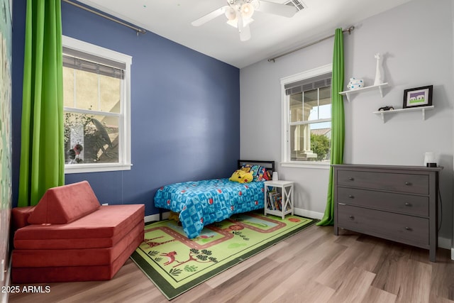 bedroom featuring visible vents, a ceiling fan, baseboards, and wood finished floors