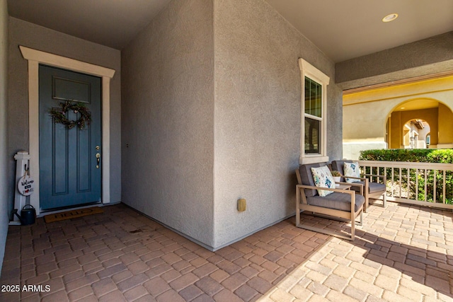 property entrance with stucco siding and a porch