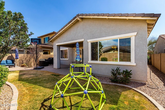 back of house with a patio area, stucco siding, a lawn, and a fenced backyard