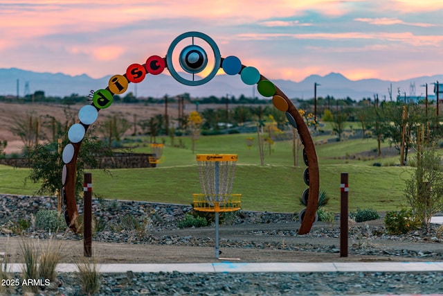 playground at dusk featuring a mountain view and a lawn