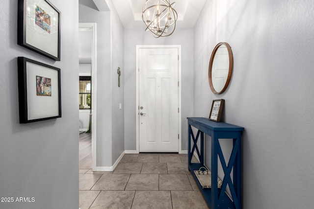 entryway with tile patterned flooring, baseboards, and a chandelier