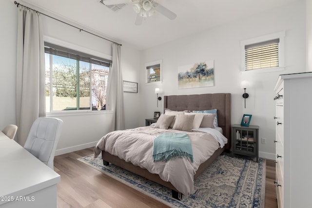 bedroom with a ceiling fan, visible vents, baseboards, and light wood finished floors