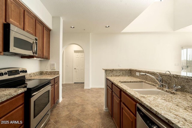 kitchen featuring light stone counters, sink, and appliances with stainless steel finishes