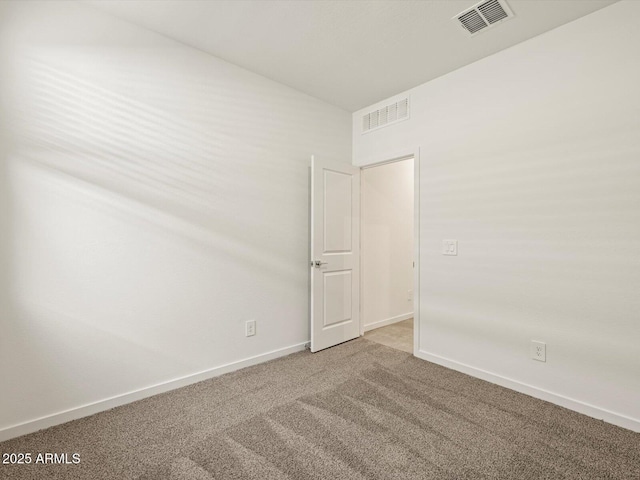 empty room with carpet flooring, visible vents, and baseboards