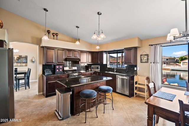 20657 N 56th Ave, Glendale, AZ 85308 - kitchen featuring stainless steel appliances, dark countertops, under cabinet range hood, backsplash, and vaulted ceiling