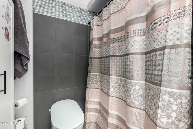 bathroom featuring toilet, tile walls, and a shower with shower curtain