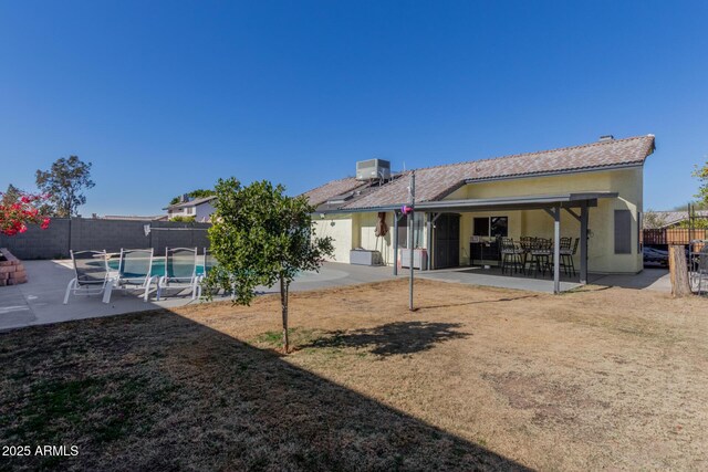 back of house with a fenced in pool, central air condition unit, a lawn, and a patio