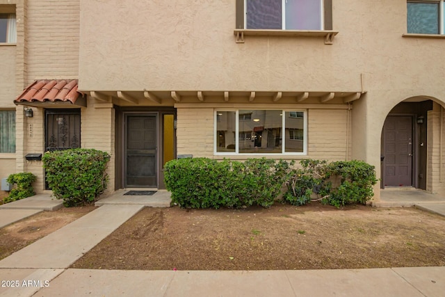 property entrance featuring a tile roof and stucco siding