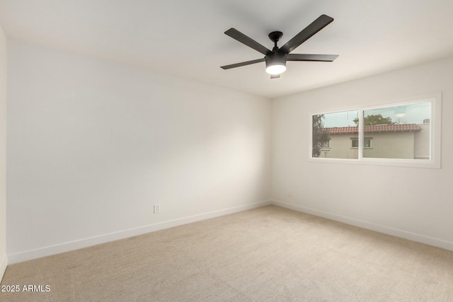 carpeted spare room featuring a ceiling fan and baseboards