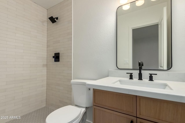 full bath featuring a tile shower, vanity, and toilet