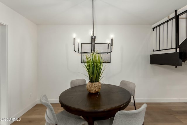 dining room featuring stairway, an inviting chandelier, wood finished floors, and baseboards