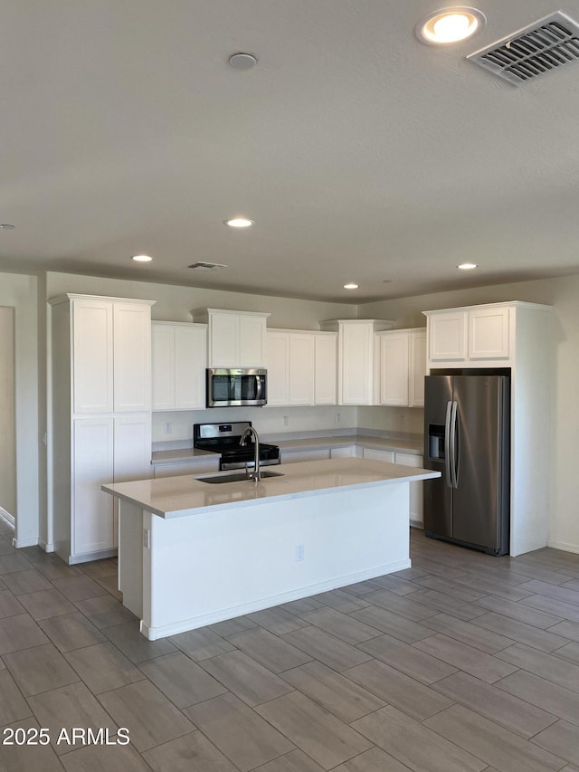 2181 N 211th Dr, Buckeye, AZ 85396 - kitchen with appliances with stainless steel finishes, a sink, a kitchen island with sink, light countertops, and white cabinetry