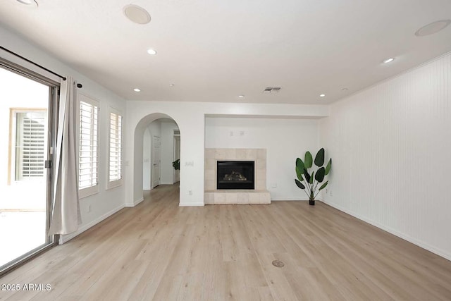 3931 E Crest Ln, Phoenix, AZ 85050 - unfurnished living room featuring light wood-style floors, arched walkways, baseboards, recessed lighting, and a tiled fireplace