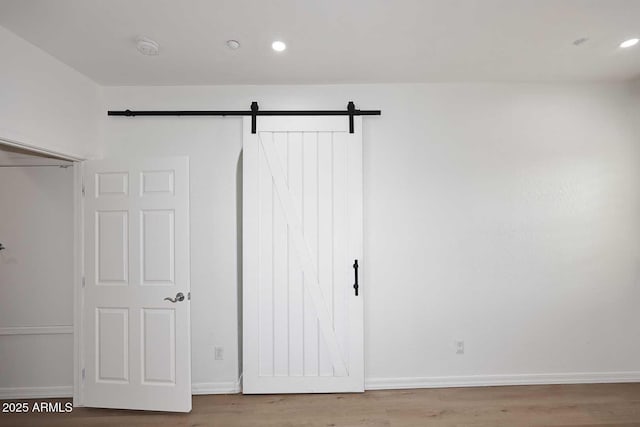 3931 E Crest Ln, Phoenix, AZ 85050 - unfurnished bedroom with a barn door, wood finished floors, baseboards, and recessed lighting