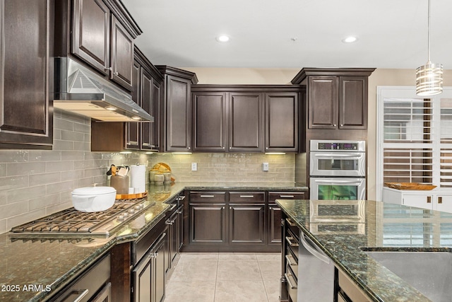 kitchen featuring under cabinet range hood, dark stone counters, stainless steel appliances, backsplash, and light tile patterned flooring