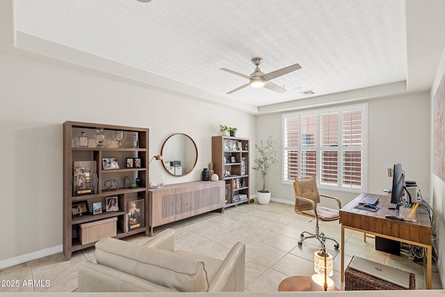 office space featuring tile patterned floors, baseboards, a ceiling fan, and a raised ceiling