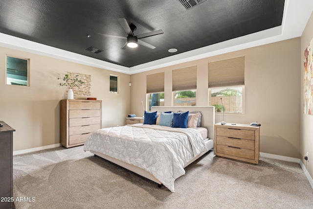 bedroom featuring baseboards, visible vents, a tray ceiling, and light colored carpet