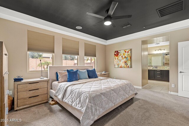 bedroom featuring visible vents, a tray ceiling, light colored carpet, and connected bathroom