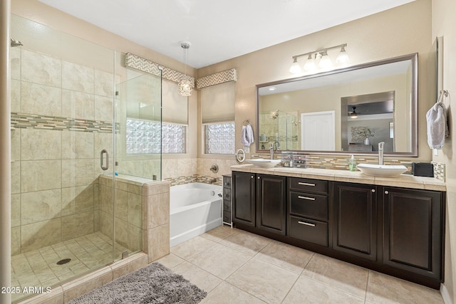 full bath featuring a sink, double vanity, tile patterned flooring, a shower stall, and a garden tub