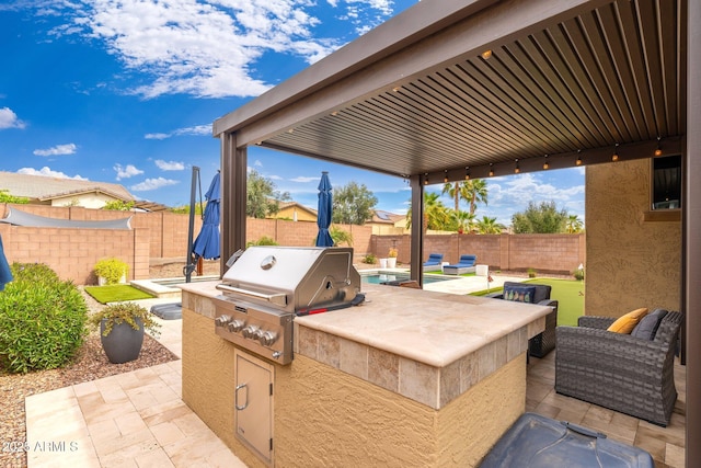 view of patio / terrace featuring grilling area, an outdoor kitchen, and a fenced backyard