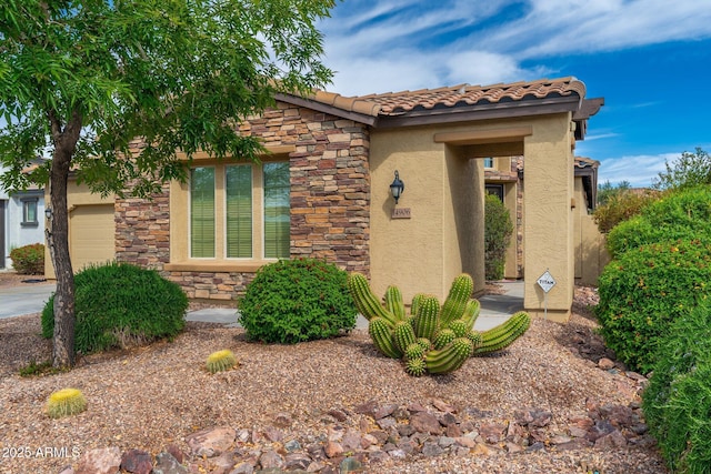 view of front of house with a garage, a tiled roof, stucco siding, and stone siding