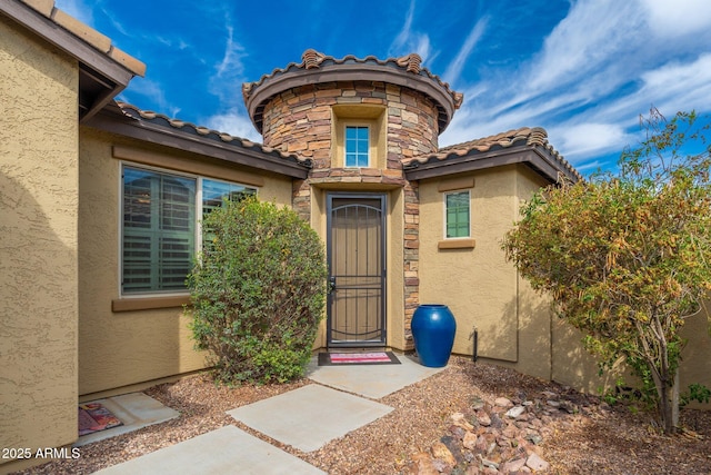 entrance to property featuring a tile roof and stucco siding
