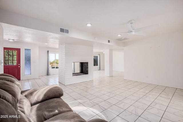 living room with a ceiling fan, visible vents, and a fireplace