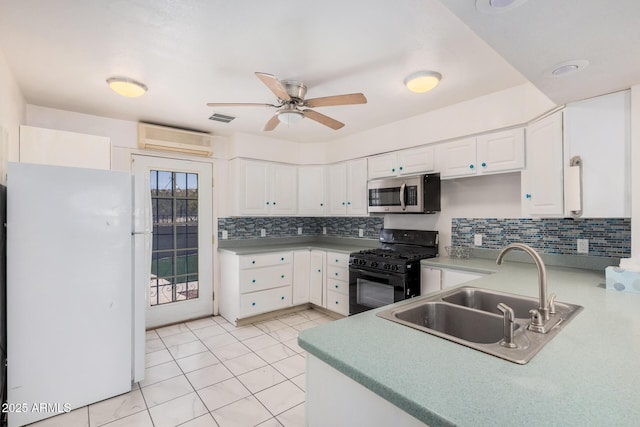 kitchen with a sink, black range with gas stovetop, an AC wall unit, freestanding refrigerator, and stainless steel microwave