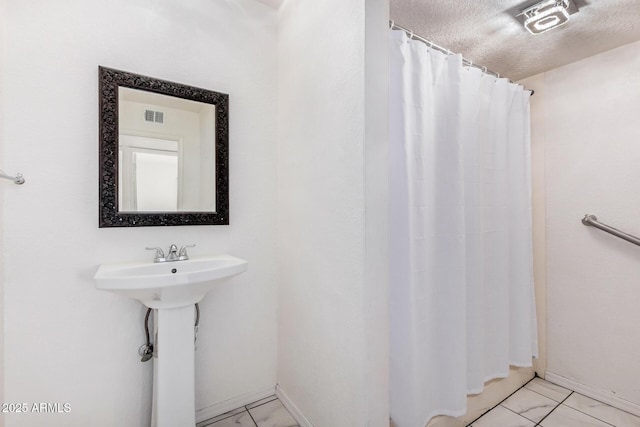 full bath with visible vents, a textured ceiling, baseboards, and curtained shower