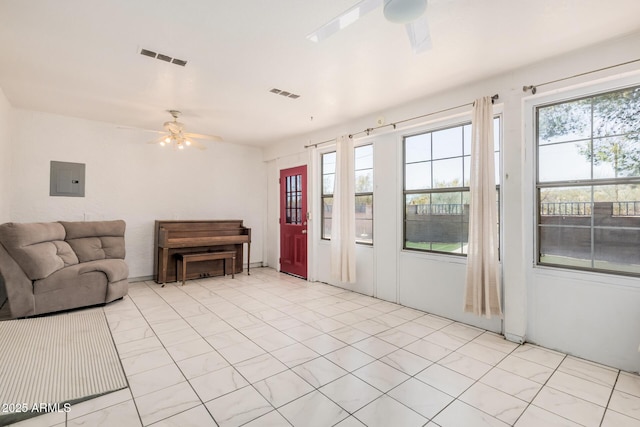 living area with visible vents, a ceiling fan, and electric panel