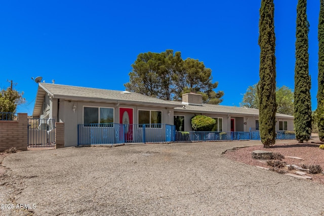 ranch-style house with fence, a chimney, and a gate