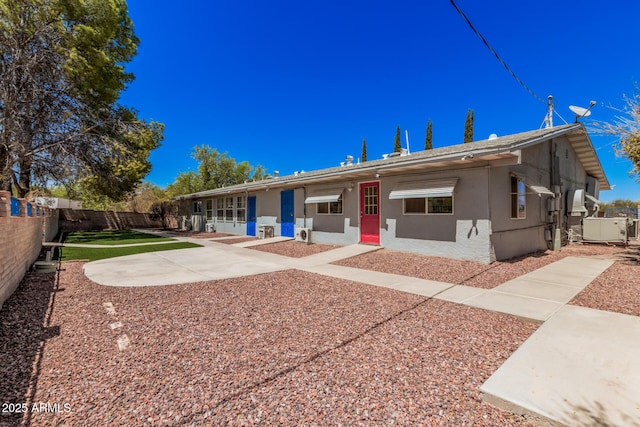 rear view of property featuring stucco siding and fence