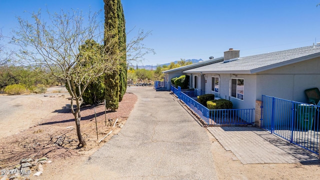 view of property exterior with fence, a chimney, and stucco siding
