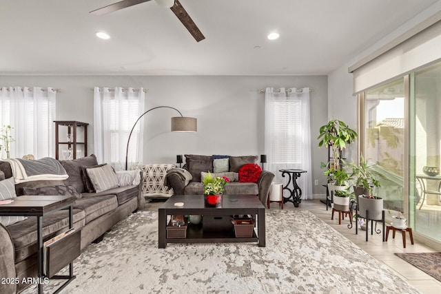 living room with ceiling fan, light wood-type flooring, and a wealth of natural light