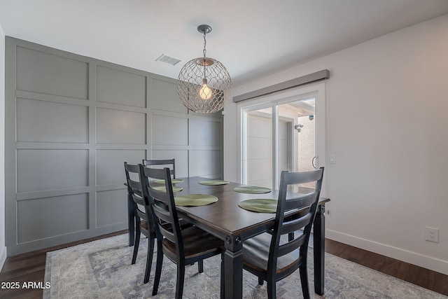 dining area featuring visible vents, baseboards, dark wood-style flooring, and a decorative wall