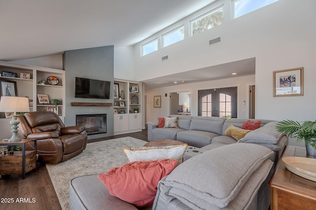 living room featuring a glass covered fireplace, high vaulted ceiling, dark wood-style flooring, and visible vents